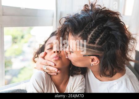 Mutter küssen Tochter auf Wange Stockfoto