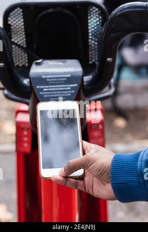 Hand des Mannes, der am Parkplatz ein Fahrrad über ein Smartphone ausgeliehen hat Station Stockfoto