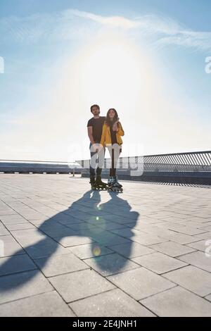 Junger Mann mit Frau auf Pier gegen Himmel während stehen Sonniger Tag Stockfoto