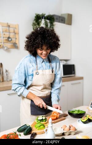 Porträt der jungen Frau Schneiden von Gemüse in der Küche Stockfoto