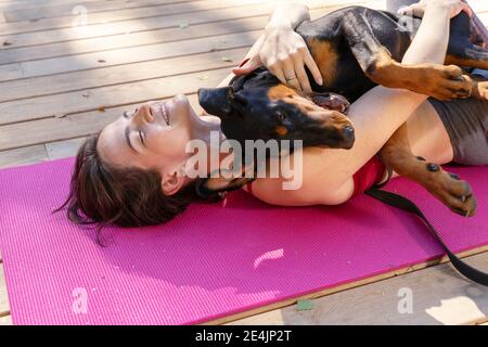 Junge schöne Frau ist in der Gymnastik im Park mit einem doberman Hund beschäftigt. Stockfoto