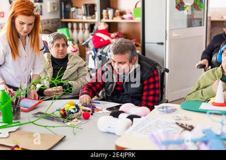 Weibliche Krankenschwester tun kreative Handwerk mit behinderten Mann und Frau Im Pflegeheim Stockfoto