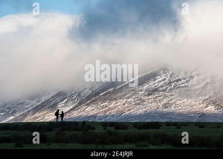 Atemberaubende Landschaft Bild von Skiddaw schneebedeckten Bergkette in Lake District im Winter mit niedrigen Wolken um Gipfel Stockfoto