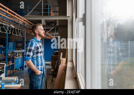 Porträt des Zimmermanns, der durch das Fenster in der Produktionshalle schaut Stockfoto