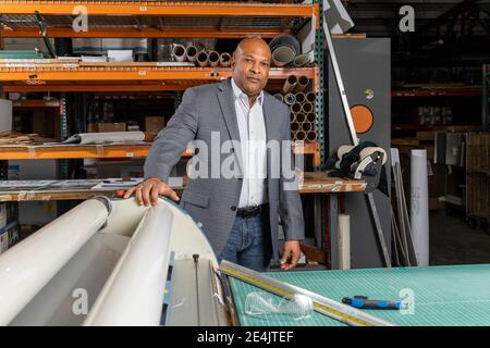 Lächelnder Vorgesetzter, der Papier in die Druckmaschine legt, während er im Geschäft arbeitet Stockfoto