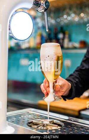 Hand des Barkeepers mit einem vollen Glas frisch gegossenem Bier Stockfoto