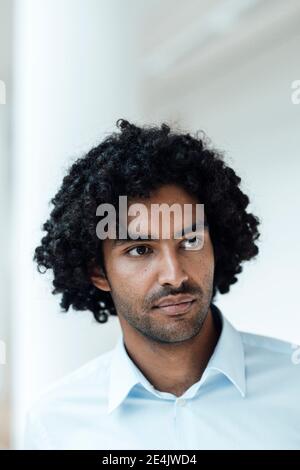 Nachdenklich junge männliche Profi mit lockigen schwarzen Haaren wegschauen Im Büro Stockfoto