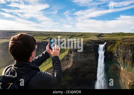 Tourist fotografieren Haifoss Wasserfall durch Handy während In Island stehen Stockfoto