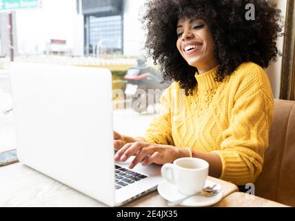 Glückliche Frau mit Laptop, während sie im Café sitzt Stockfoto