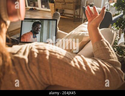 Junger Mann lächelt auf Laptop-Bildschirm während Videoanruf mit Frau Stockfoto