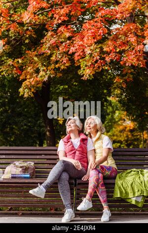 Freundinnen in Sportkleidung mit geschlossenen Augen im Herbst park an sonnigen Tag Stockfoto