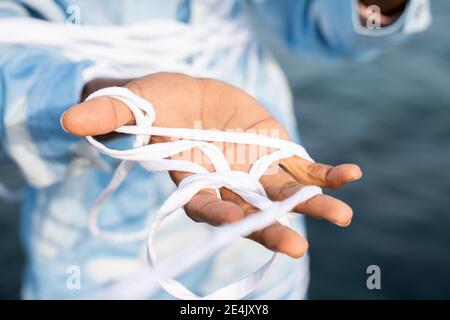 Nahaufnahme von Menschenhand, die in einem Seil im Freien gefangen ist Stockfoto