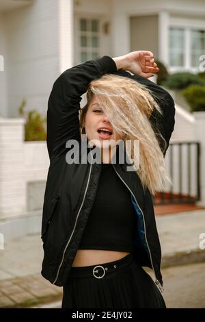 Blonde Hipster Frau mit erhobenen Armen auf der Straße stehen Stockfoto