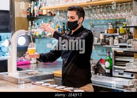 Porträt des Barkeepers mit Schutzmaske Bier serviert Stockfoto