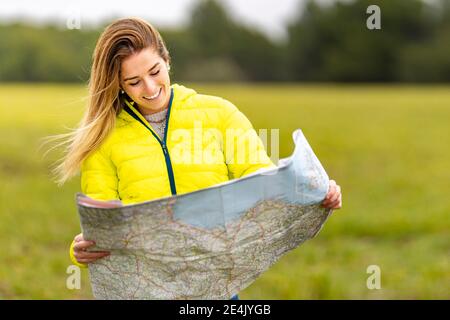 Portrait von jungen schönen Frau lächeln, während im Freien mit stehen Karte in den Händen Stockfoto