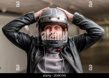 Fröhlicher reifer Mann mit Helm, während er auf dem Parkplatz sitzt Stockfoto