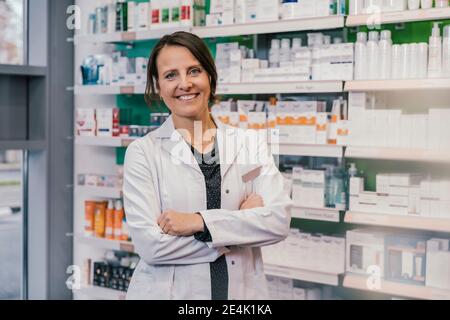 Selbstbewusste Apothekerin mit gekreuzten Armen in der Apotheke Stockfoto