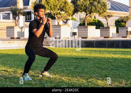 Junger Mann, der im Park auf Gras steht und trainiert Bei Sonnenuntergang Stockfoto
