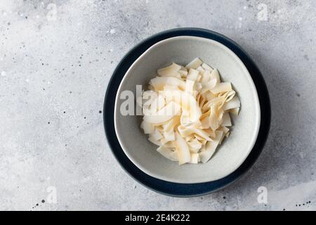 Kokosnussspäne in blauer Keramikschale. Veganes Lebensmittelkonzept Stockfoto