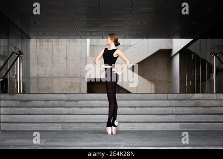 Ballerina in schwarzem Trikot in modernem Betongebäude Stockfoto