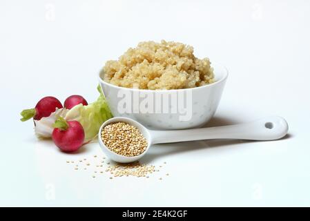 Quinoa, gekochte Quinoa in einer Schüssel, ungekochte Quinoa-Samen in einem Porzellanlöffel, Chenopodium Quinoa Stockfoto