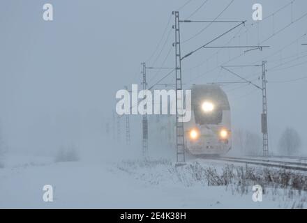 Ein Personenzug kommt durch einen schweren Schneesturm in der Winterzeit Stockfoto