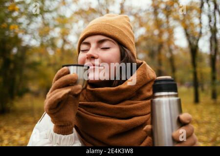 Junge Frau mit geschlossenen Augen riechenden Tee im Herbst Park Stockfoto