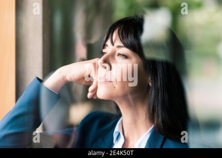 Durchdachte Geschäftsfrau im Büro durch Glas gesehen Stockfoto