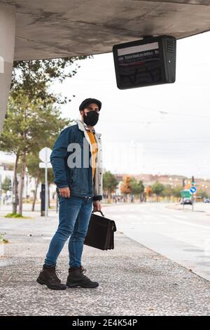 Pendler mit Hut warten auf Bus während COVID-19 Stockfoto