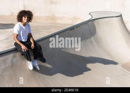 Sportler lächelnd, während sie auf der Sportrampe im Skateboard Park sitzen Stockfoto