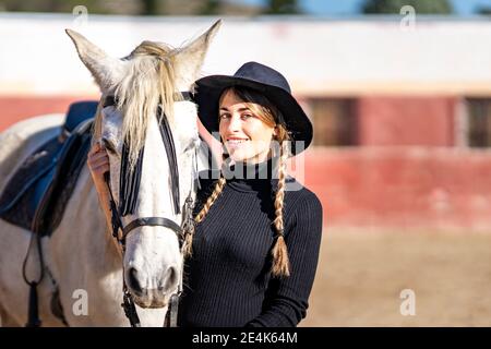 Porträt einer lächelnden Frau mit Pferd im Fahrerlager Stockfoto