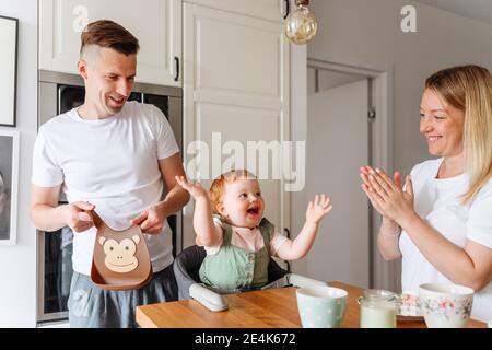 Glückliche Familie mit Baby Tochter am Küchentisch Stockfoto