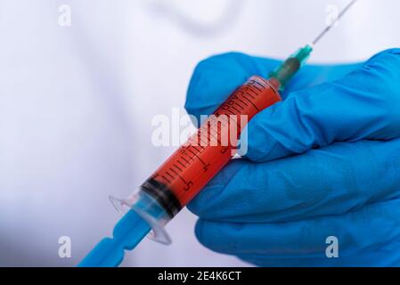 Die Hand eines Arztes in medizinischen Handschuhen hält eine Spritze mit Blut. Das Konzept der medizinischen Tests und Untersuchungen. Stockfoto