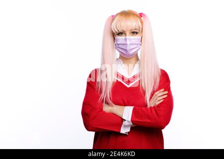 Schöne junge Frau mit Armen gekreuzt tragen Gesichtsmaske während Pandemie Stockfoto