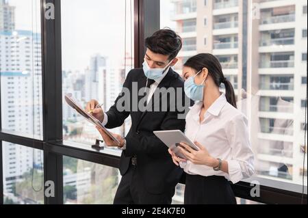 Multiethnische Geschäftskollegen tragen Gesichtsmaske diskutieren und Beratung in neuen normalen Büro im Geschäftsviertel. Während Pandemie des Coronavirus, Stockfoto