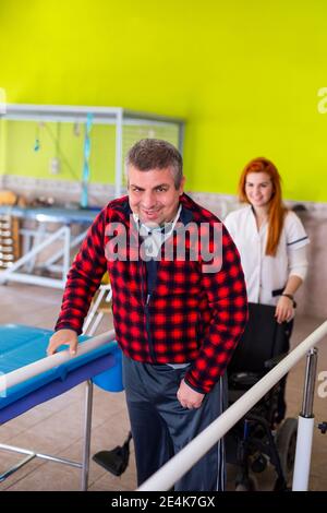 Lächelnder behinderter Mann, der mit einer Krankenschwester im Pflegeheim steht Stockfoto