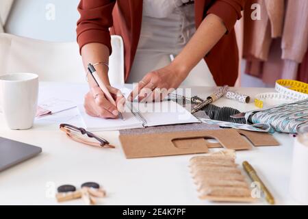 Weibliche Mode professionelle Schreiben in persönlichen Veranstalter am Schreibtisch in Designstudio Stockfoto