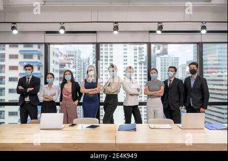 Multiethnisches Business-Team selbstbewusst tragen Gesichtsmaske stehen in Meeting-Raum im Coworking Space. Neue normale Büro während Pandemie von Coronavirus, Co Stockfoto