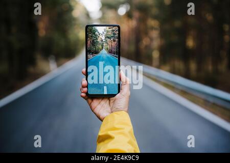Womans Hand halten Smartphone, fotografieren leere Landstraße Stockfoto