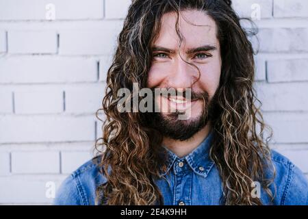 Lächelnder junger Mann mit grauen Augen gegen die Ziegelmauer Stockfoto