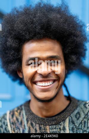 Nahaufnahme eines lächelnden jungen Mannes mit lockigen Haaren Stockfoto