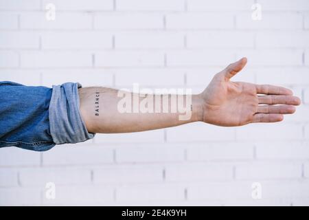 Hand des Mannes mit Tätowierung gegen Ziegelwand Stockfoto