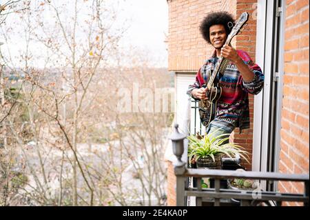 Afromännlicher Musiker, der zu Hause Saxophon auf dem Balkon übt Stockfoto