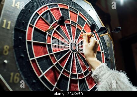 Die Hand der Frau sammelt Darts vom Brett Stockfoto