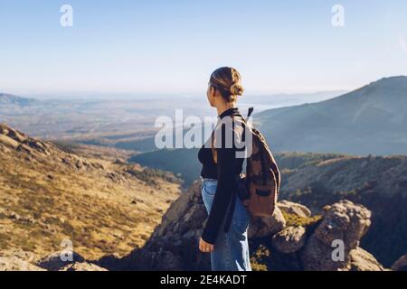 Weibliche Wandererin mit Rucksack, die beim Stehen die Ansicht ansieht Spitze des Berges Stockfoto