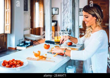Schöne junge Frau lächelt und hackt Gemüse zum Abendessen Stockfoto