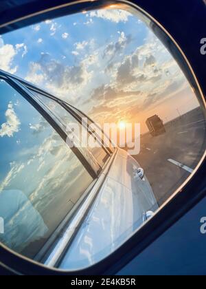 Nahaufnahme von seltenen bewölkten Himmel und Sonnenuntergang Blick von der Seite Spiegel des Autos, schöne Szene der Straße Spur zu, Stockfoto