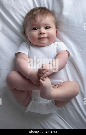 Baby Boy auf Bett liegend Stockfoto