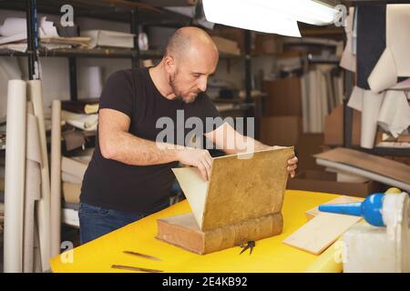 Buchbinder stellt altes Buch in Handwerkswerkstatt wieder her Stockfoto