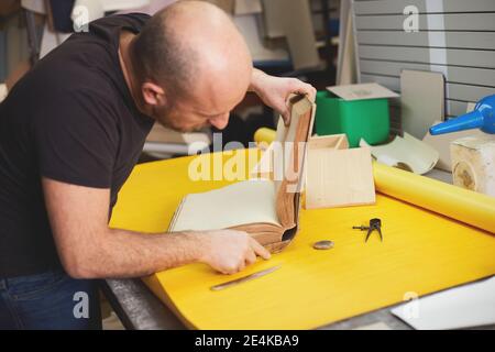 Buchbinder stellt altes Buch in Handwerkswerkstatt wieder her Stockfoto